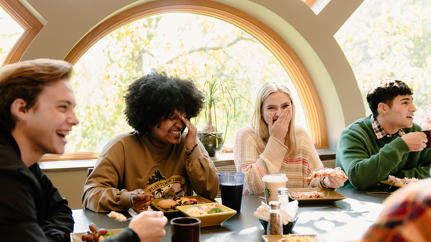 Several students eating in the dining hall together