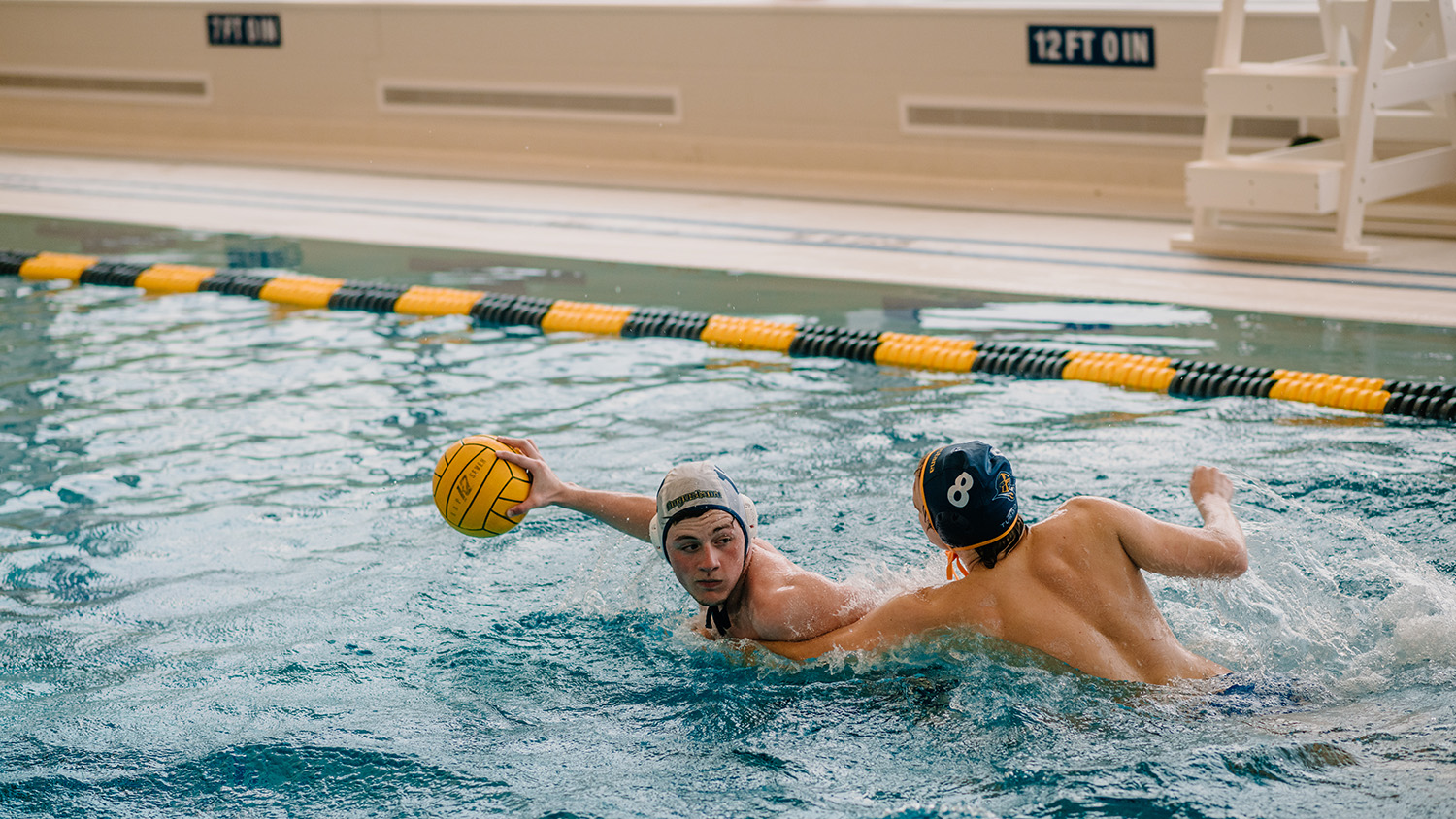 Two students playing water polo in the swimming pool