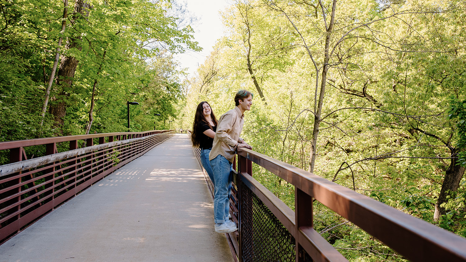 Two students climb on the fence of a bridge to get a better view of the Slough