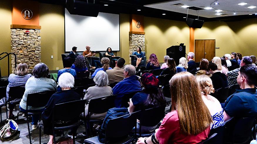 Three panelists and a moderator on stage, April 25