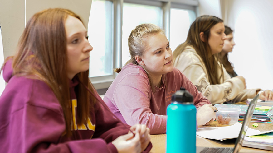 Four students listening in a classroom