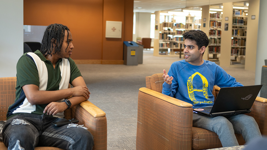 Two students talking in the library