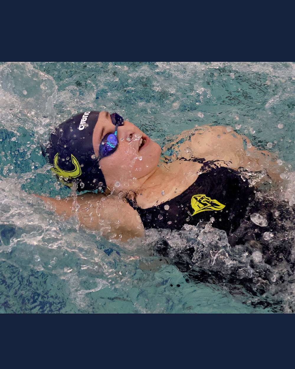 A close shot of a student-athlete swimming backstroke