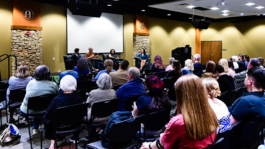 Three panelists and a moderator on stage, April 25