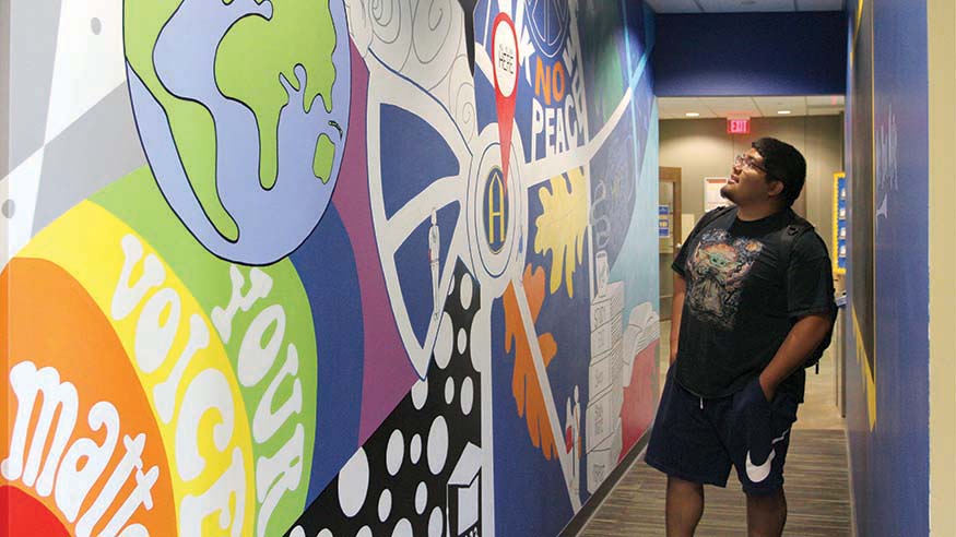 Sophomore Jesus Murillo in front of the You Belong Here Lounge mural