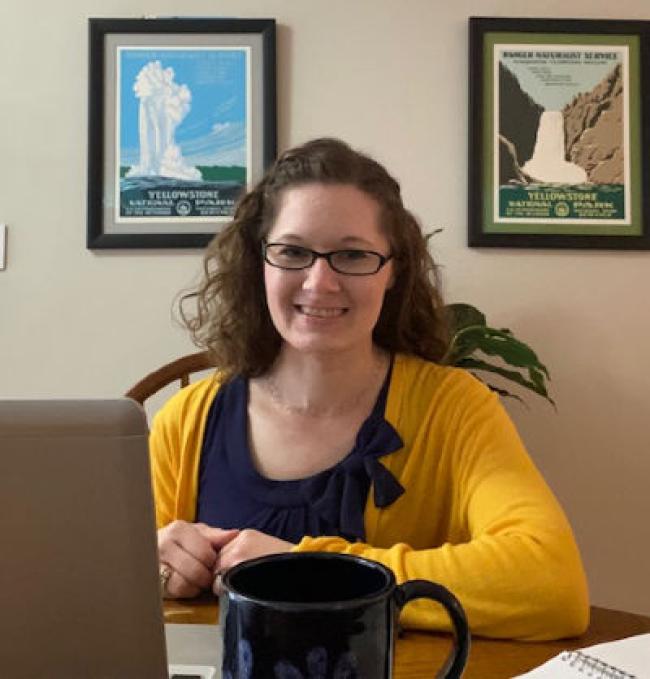 Danielle Roman posing near her laptop in blue and gold.