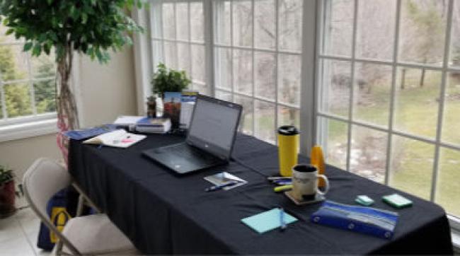 Karen Peterson, using a long table with laptop on it with window view