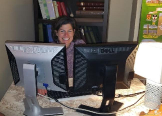Wendy Kelley at the home office with dual monitors and lap shade in corner.
