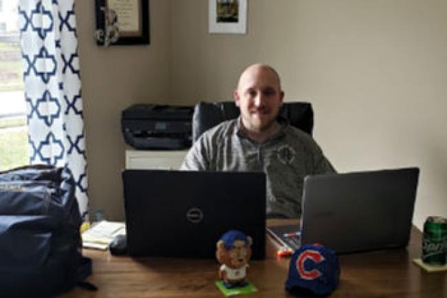 Wes Brooks sitting behind desk with 2 laptops in front of him