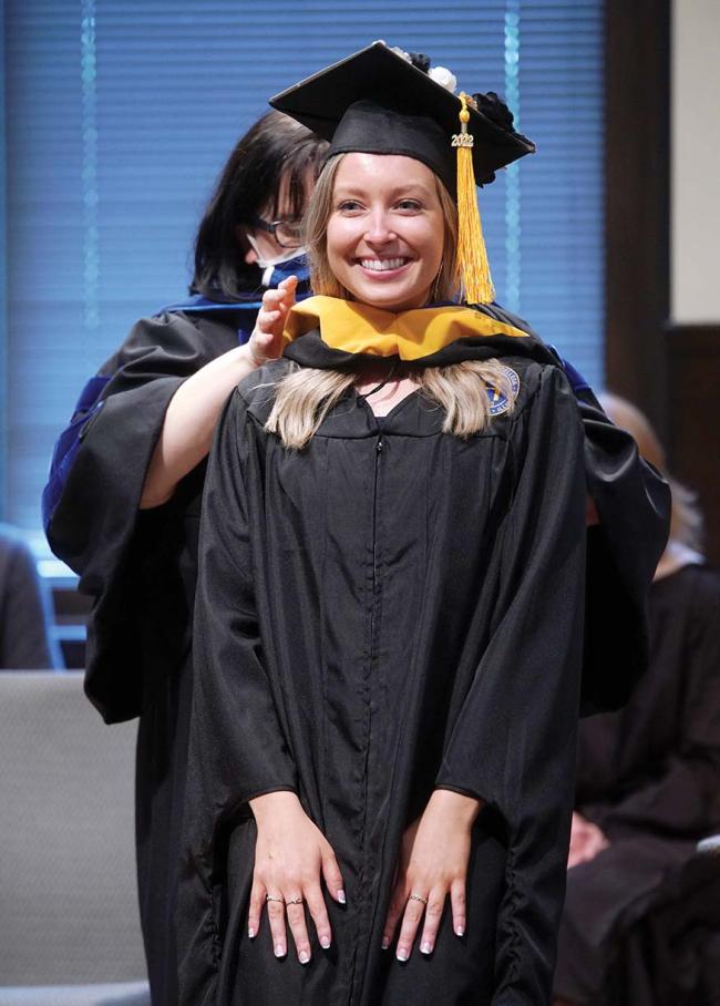  of Naperville, Ill. Here, Dr. Allison Haskill, MS-SLP program director, places the hood over DuBois’ head and aroun