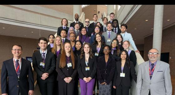 students standing on staircase smiling at the camera.